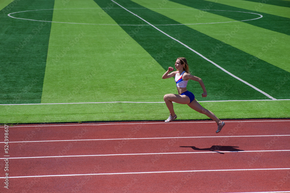Fototapeta premium Young caucasian woman is engaged in jogging at the stadium outdoors.