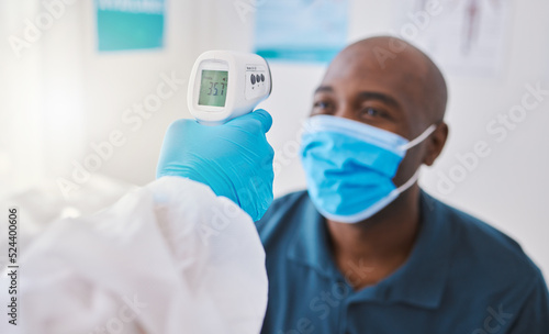 Checking for covid  corona or fever with a patient wearing a mask for hygiene  sickness or flu symptoms in a health clinic. Medical doctor holding a thermometer to scan the temperature of a patient