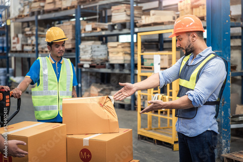 Supervisor, manager or boss to angry, scold or mad to worker, employee inside distribution warehouse about bad, damage, broken or dented of cardboard box package. May called carton, parcel, cargo. 