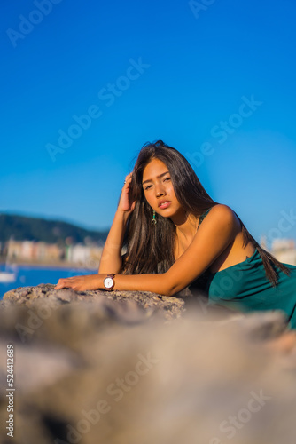 A young latin woman enjoying a green dress on summer vacations, looking at the sea