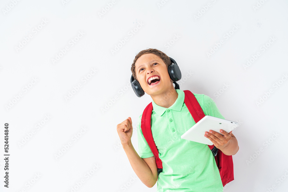 E-learning at school. A happy student wearing headphones with a tablet computer in his hands. Recommending a Remote online school on a white background in the studio. E-learning at school. A happy student wearing headphones with a tablet computer in his hands. Recommending a Remote online school on a white background in the studio.
