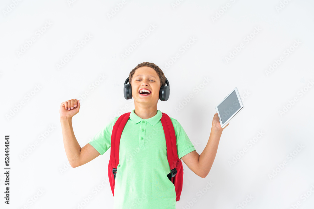E-learning at school. A happy student wearing headphones with a tablet computer in his hands. Recommending a Remote online school on a white background in the studio. E-learning at school. A happy student wearing headphones with a tablet computer in his hands. Recommending a Remote online school on a white background in the studio.
