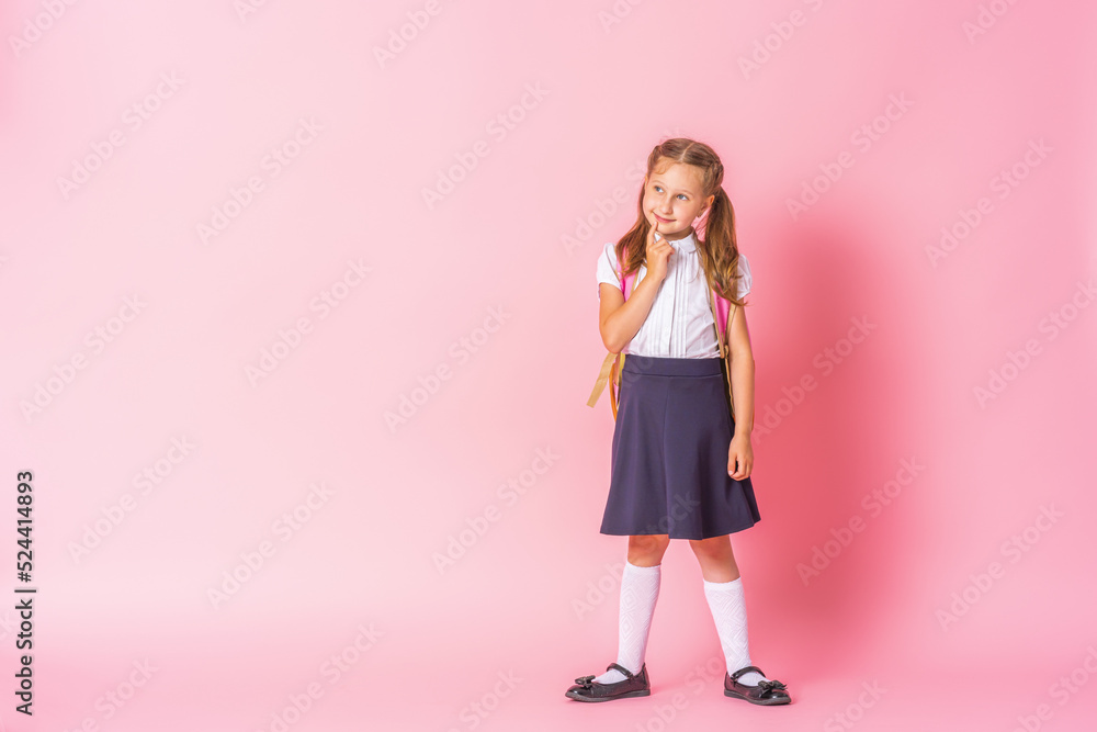 thoughtful schoolgirl in uniform stands and thinks on a pink background. The child ponders his decision, reflects on the correct answer. Space for copying. thoughtful schoolgirl in uniform stands and thinks on a pink background. The child ponders his decision, reflects on the correct answer. Space for copying.