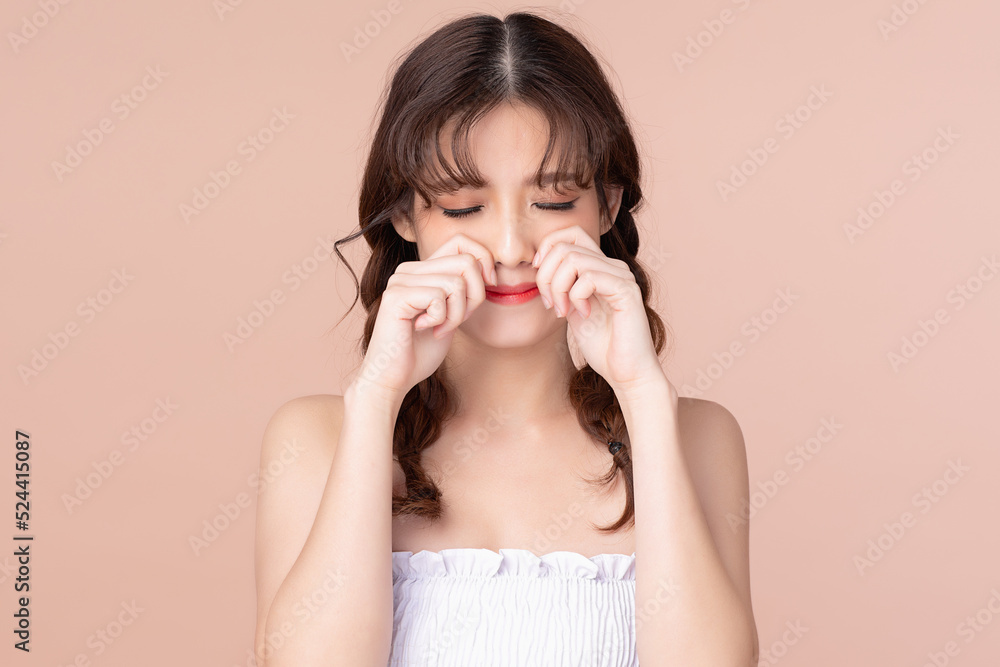 Portrait of displeased upset female with two pigtails frowns face as going to cry, being discontent and unhappy isolated over on beige pink studio background. Dissapointed young woman has troubles Portrait of displeased upset female with two pigtails frowns face as going to cry, being discontent and unhappy isolated over on beige pink studio background. Dissapointed young woman has troubles