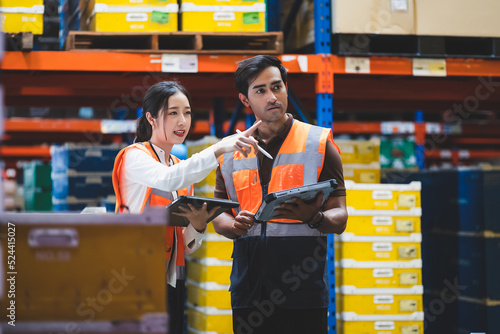 Warehouse worker and manager checks stock and inventory with using digital tablet computer in the retail warehouse full of shelves with goods. Working in logistics, Distribution center.