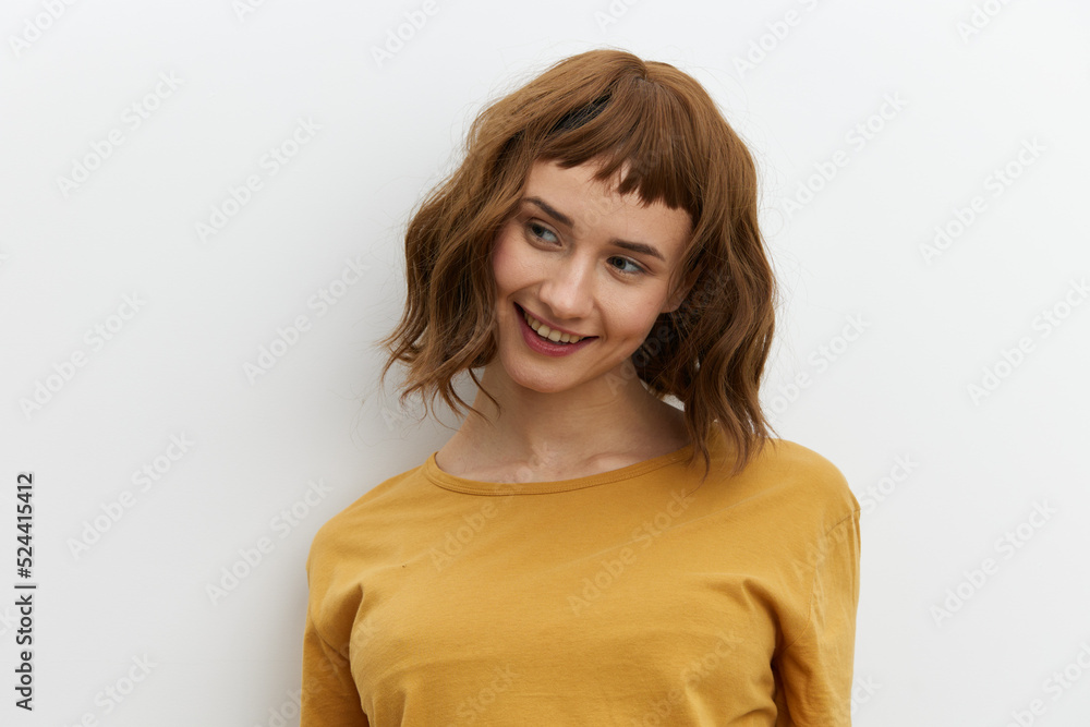 a beautiful, sweet, relaxed woman stands on a light background in a yellow T-shirt and looks away with a pleasant smile. Horizontal photo with an empty space for inserting an advertising layout a beautiful, sweet, relaxed woman stands on a light background in a yellow T-shirt and looks away with a pleasant smile. Horizontal photo with an empty space for inserting an advertising layout