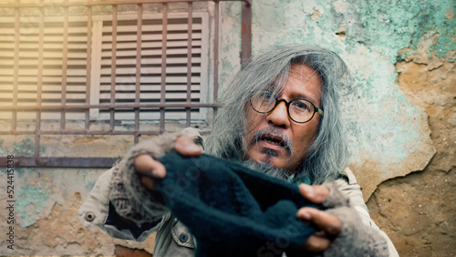 Photography homeless man, dirty dressed, is reaching out for help from passersby asking for food and money with pitiful eyes