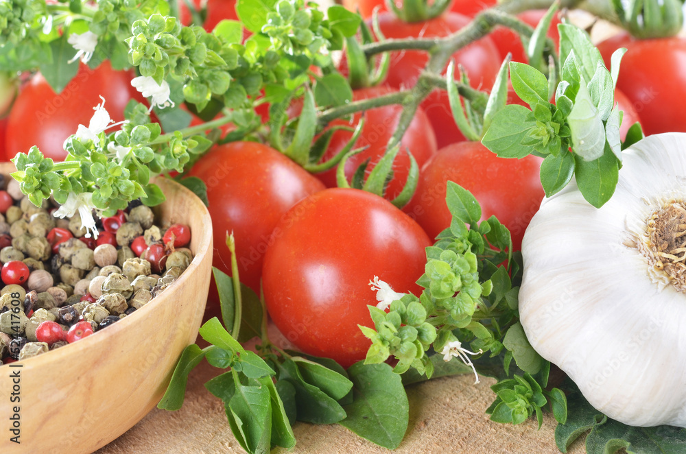 Ripe cherry tomatoes, peppercorns, garlic, basil, on a wooden table close-up Ripe cherry tomatoes, peppercorns, garlic, basil, on a wooden table close-up