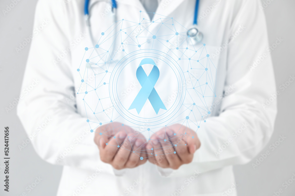 Doctor and blue ribbon on virtual screen against light background. Prostate cancer awareness concept Doctor and blue ribbon on virtual screen against light background. Prostate cancer awareness concept