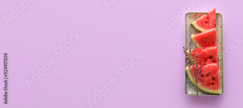 Plate with cut sweet watermelon on lilac background with space for text