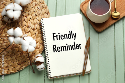 Schilderij op canvas Notebook with text FRIENDLY REMINDER and pen on green wooden background