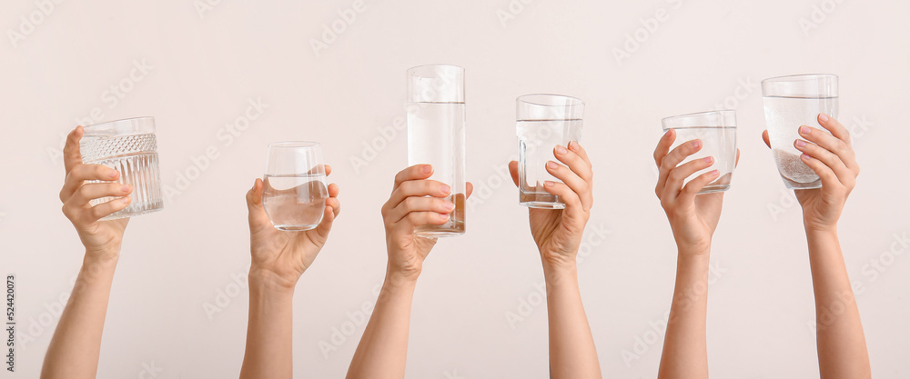 Female hands with glasses of water on light background Female hands with glasses of water on light background