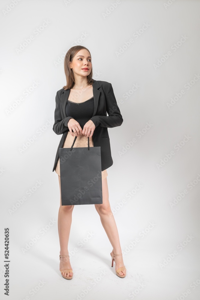 Full length body portrait of a young beautiful asian female businesswoman wearing stylish business attire with skirt holding a black color shopping paper bag elegantly and cool stylish Full length body portrait of a young beautiful asian female businesswoman wearing stylish business attire with skirt holding a black color shopping paper bag elegantly and cool stylish