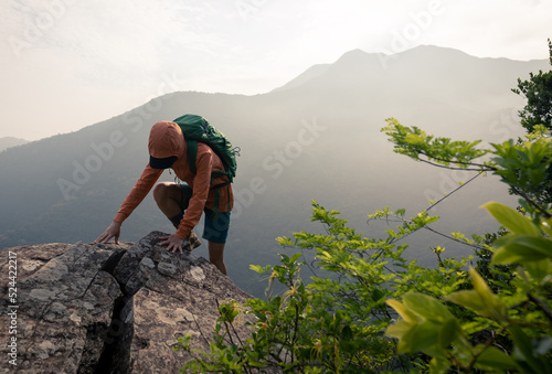 Suceesful woman hiker climbing up at the cliff edge on mountain top