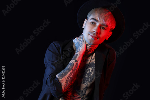 Young tattooed man on black...