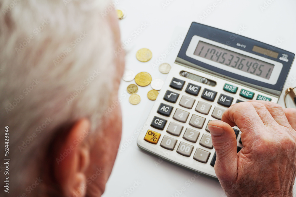 Upset depressed Senior man sitting at the table and calculating finances. Old man checking bills. Man counting coins on the table. Pension calculation concept Upset depressed Senior man sitting at the table and calculating finances. Old man checking bills. Man counting coins on the table. Pension calculation concept
