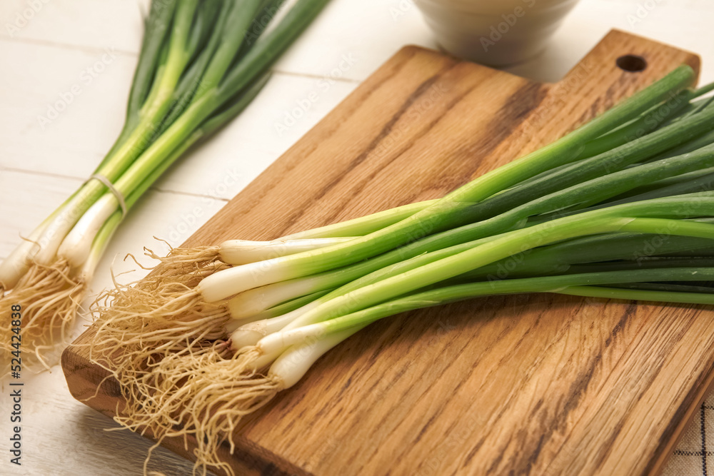 Board with bunch of fresh green onion on light wooden background, closeup Board with bunch of fresh green onion on light wooden background, closeup
