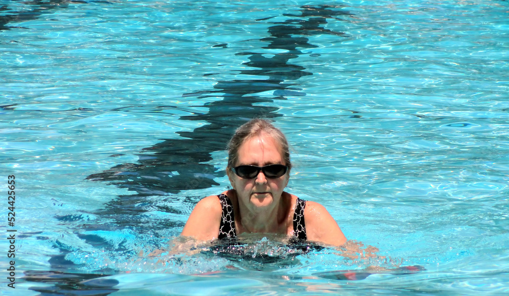 Naklejka premium Mature female senior in the swimming pool outside.
