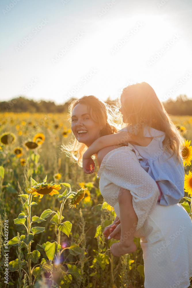 Mom hugs her little daughter. A beautiful young woman with a 4-year-old child in her arms in a sunflower field. Summer. Mom hugs her little daughter. A beautiful young woman with a 4-year-old child in her arms in a sunflower field. Summer.