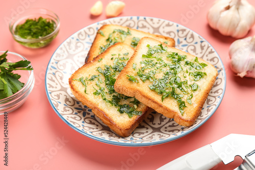 Plate with slices of toasted garlic bread on pink background, closeup