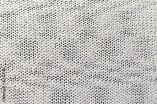 Knitted white pattern closeup. Soft sweater texture, detailed yarn background. Natural woolen fabric, a fragment of a jersey pullover. Trendy backdrop for print, web design.