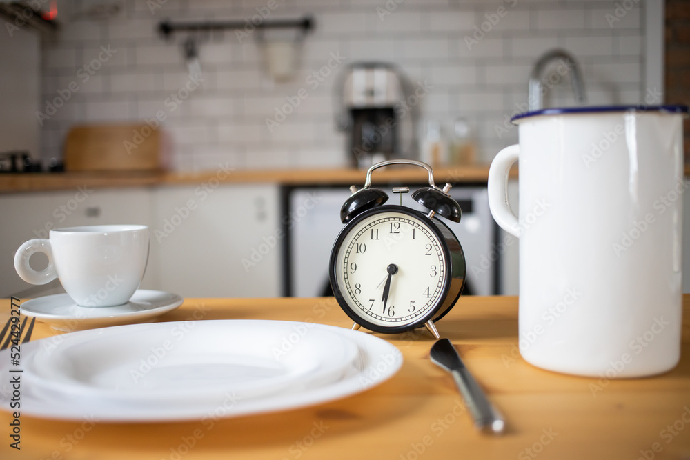 intermittent fasting concept alarm clock on kitchen table intermittent fasting concept alarm clock on kitchen table