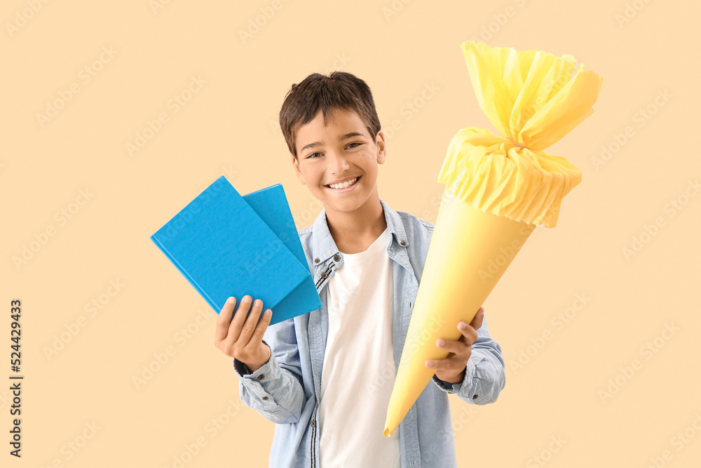 Little boy with yellow school cone and books on beige background Little boy with yellow school cone and books on beige background