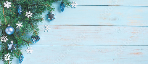 Christmas light green wooden background, corner set. Fir branches, blue silver baubles, stars, hearts, cones, white snowflakes. Xmas, New Year festive decoration, top view, copy space.