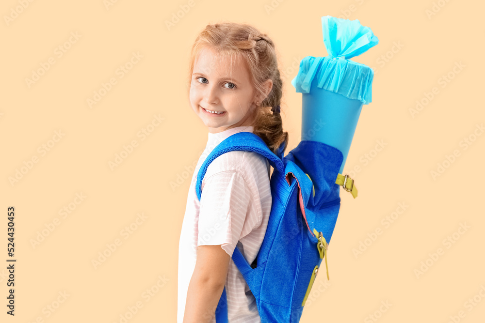 Cute little girl with school cone and backpack on beige background Cute little girl with school cone and backpack on beige background