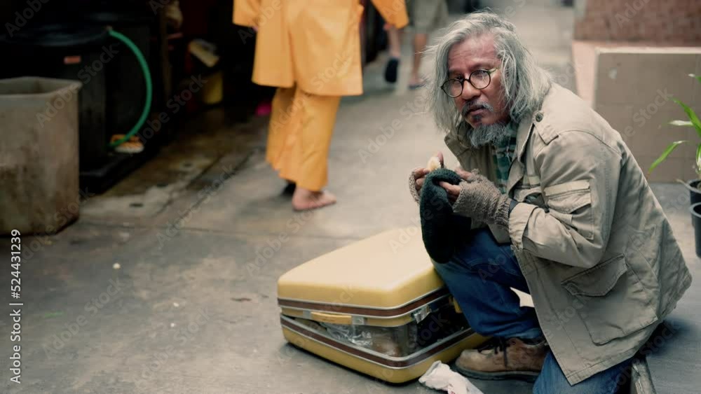 4K, A homeless Asian man sits by the sidewalk asking for donations from passersby in despair with no work and home and in hunger in need of beggar. Elderly man with no work, no home, and on roadside. 4K, A homeless Asian man sits by the sidewalk asking for donations from passersby in despair with no work and home and in hunger in need of beggar. Elderly man with no work, no home, and on roadside.