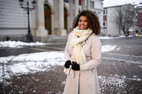 beautiful young black woman waiting in front of a theater for here friends in snow covered city photo