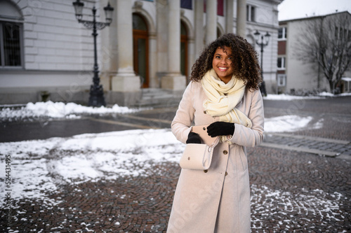 beautiful young black woman waiting in front of a theater for here friends in snow covered city