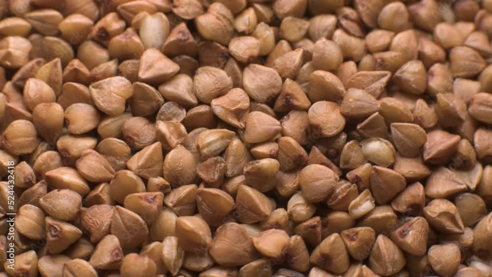 Dry raw brown buckwheat groats rotate - macro. Raw large grains of buckwheat - close-up. Vegetarian food Dry raw brown buckwheat groats rotate - macro. Raw large grains of buckwheat - close-up. Vegetarian food