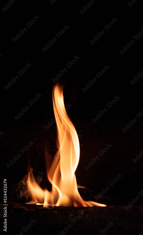 Fire flame on a dark background. Yellow tongues of fire in the fireplace. Flames concept.