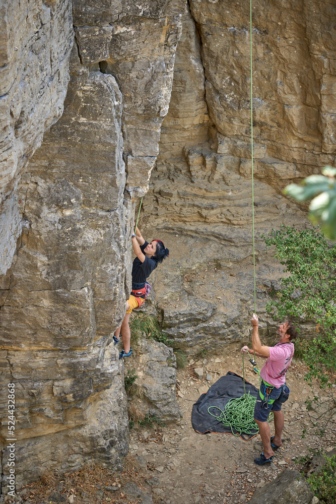 Teenage girl in a difficult rock climbing, secured by her dad in the rock gardens of Hessigheim, Neckar valley, Baden-Wuerttemberg, Germany Teenage girl in a difficult rock climbing, secured by her dad in the rock gardens of Hessigheim, Neckar valley, Baden-Wuerttemberg, Germany