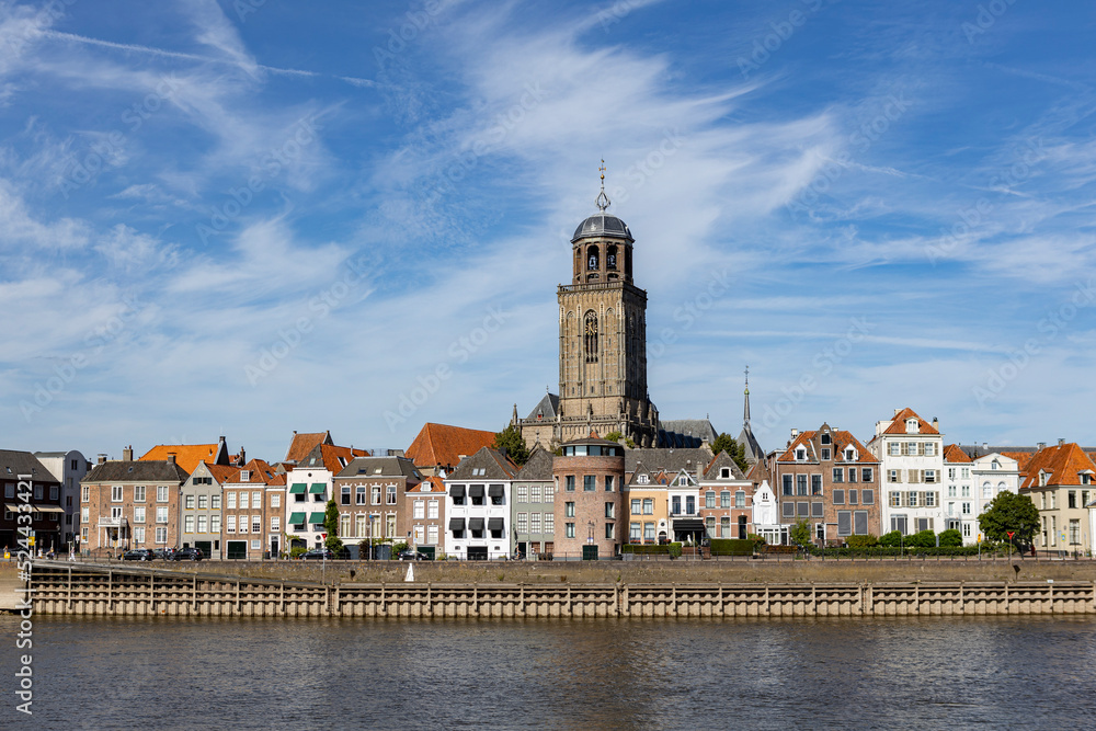 Cityscape Dutch medieval city of Deventer in The Netherlands with the principal church and facades of historic homes seen from the other side of the river IJssel that passes it
