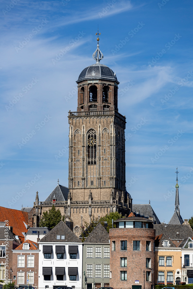 Closeup of Dutch medieval city of Deventer in The Netherlands with the principal church and facades of historic homes seen from the other side of the river IJssel that passes it