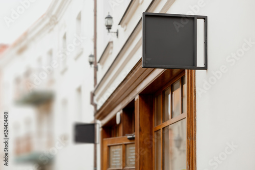 Blank signboard mock up, on the facade. Copy space for your store sign or logo. Modern empty outdoor signage, mockup to add company logo. Black square store signboard on white wall.