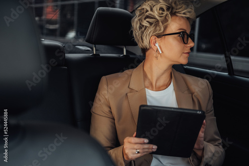 Female Entrepreneur Looking Through Window While Sitting on Back Seat of a Luxury Car