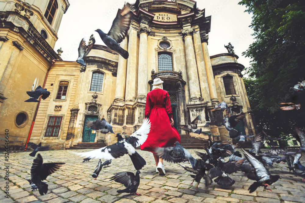 A girl in a red dress and flying doves near the Dominican Cathedral in the city of Lviv. Ukraine