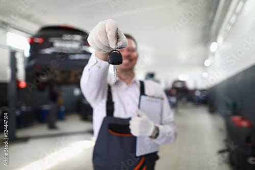 Auto mechanic holds clipboard and car keys