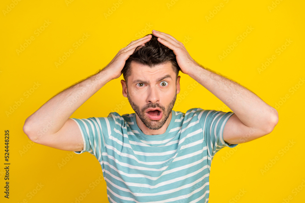 Closeup photo of young attractive guy make grimace hands hold head unexpected shock isolated on yellow color background Closeup photo of young attractive guy make grimace hands hold head unexpected shock isolated on yellow color background