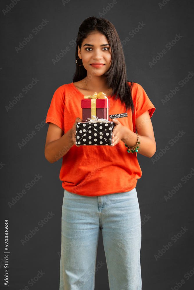 Portrait of young happy smiling Girl holding gift box on a grey background. Portrait of young happy smiling Girl holding gift box on a grey background.