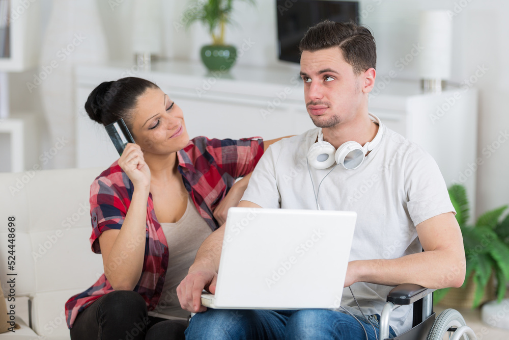 disabled man using laptop sitting next to his girlfriend disabled man using laptop sitting next to his girlfriend