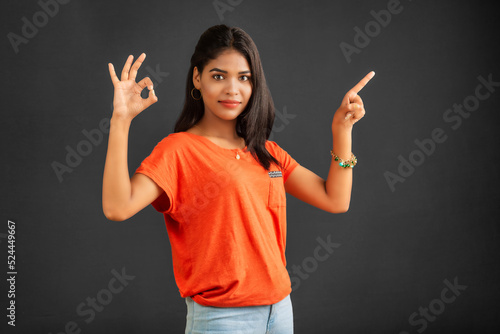 Portrait of a successful cheerful young girl pointing and presenting something with hand or finger with a happy smiling face.