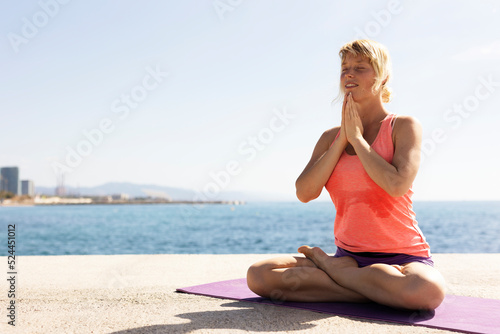 Beautiful young woman practising yoga outside. Fit woman doing stretching exercises at the beach