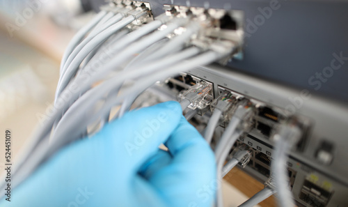 Hand of IT engineer technician with lot of internet network cable in wireless system of server room photo