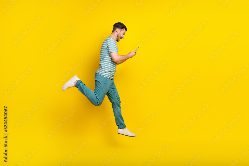 Full body photo of hooray guy run look telephone wear t-shirt jeans shoes isolated on yellow color background