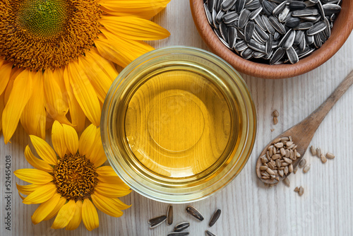 Bild auf Leinwand Sunflower oil in glass bowl and seeds on wooden table, flat lay