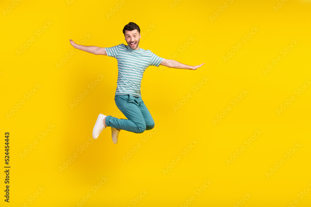 Full length photo of funny guy jump wear t-shirt jeans sneakers isolated on yellow color background